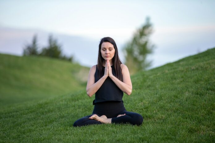 Photo by Benjamin Child woman in black tank top and black pants sitting on green grass field during daytime