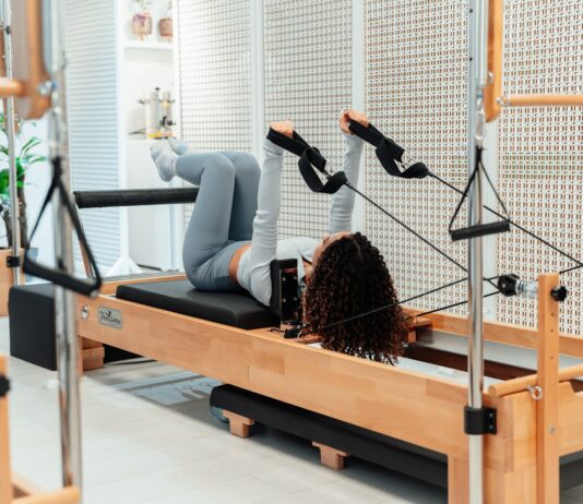 필라테스, 건강한 몸과 마음을 만들어주는 웰빙 운동의 열풍 a woman is doing exercises on a rowing machine