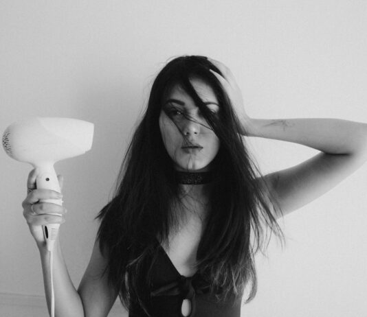 건강한 모발을 위한 올바른 관리법과 습관 woman in black tank top holding her hair