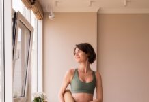 집에서 즐기는 필라테스, 바른 자세와 건강한 일상 만드는 열쇠 a woman in a green sports bra top and leggings holding a yoga mat