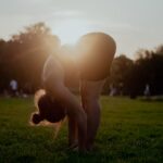 “건강하게 하루를 시작하는 작은 변화, 아침 스트레칭이 주는 선물” woman in white bikini bottom kneeling on green grass field during sunset